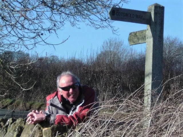 a man in sunglasses leaning against a sign