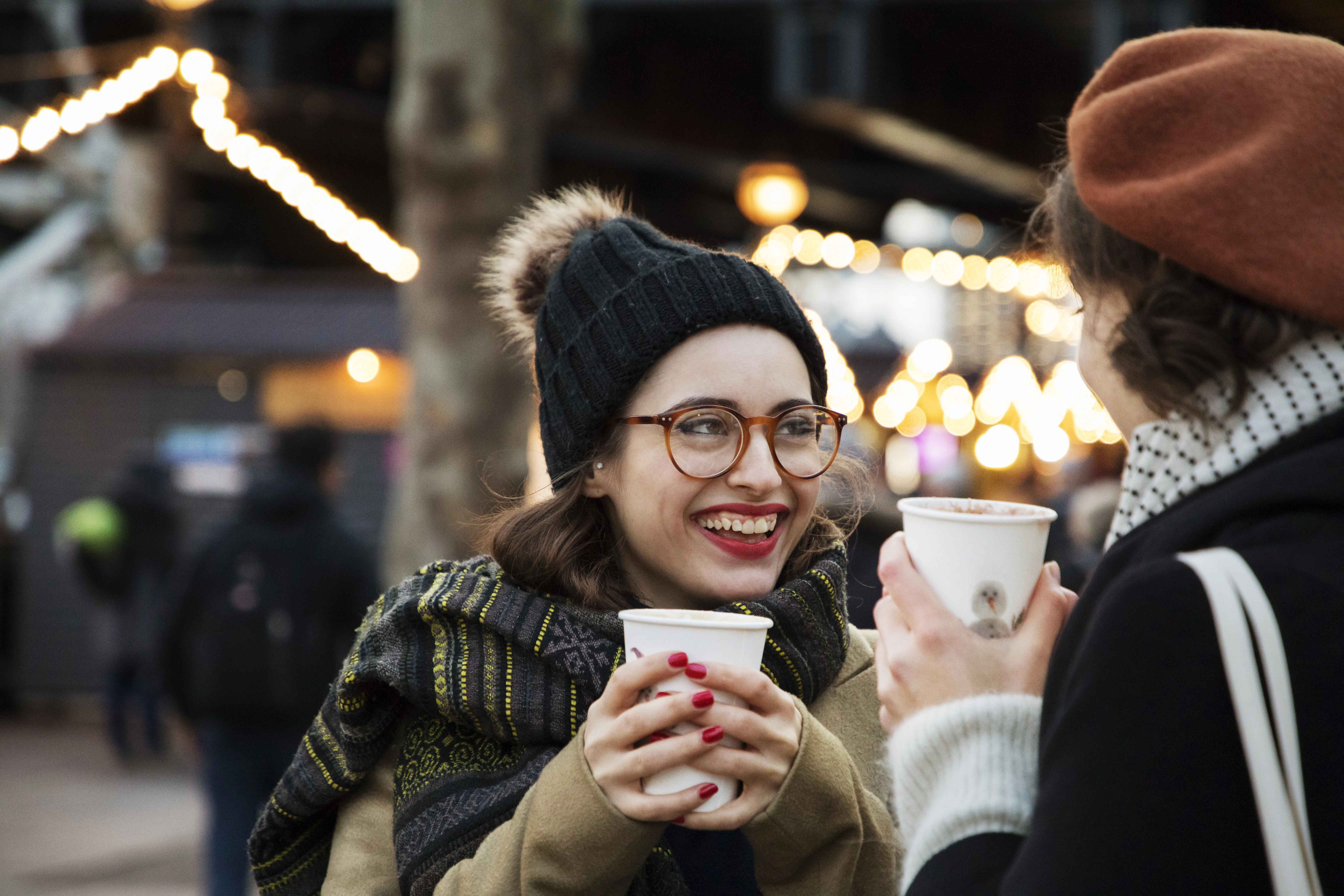 une personne tenant une tasse et un téléphone cellulaire